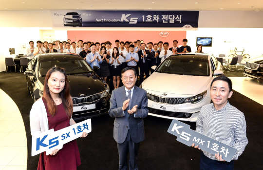 기아자동차는 27일 서울 압구정동 기아자동차 사옥에서 신형 K5 1호차 주인공을 초청해 차량을 전달하는 행사를 가졌다. 사진은 신형 K5 1호차 주인공으로 각각 선정된 김혜선씨(왼쪽), 방상철씨(오른쪽)가 김창식 기아자동차 국내영업본부장(가운데)과 기념촬영을 하고 있는 모습. <기아자동차 제공>